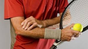 Holding elbow in pain with tennis racket in hand.